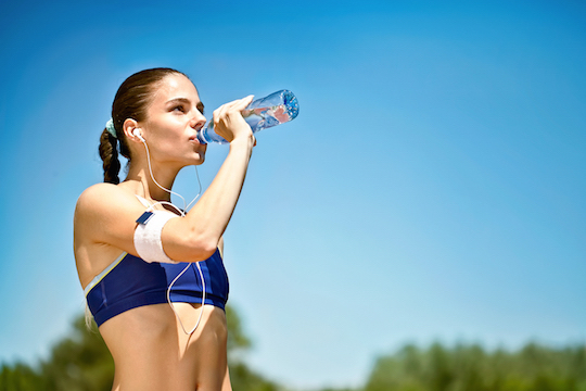 woman athlete takes a break, she drinking water, out on a run on a hot day